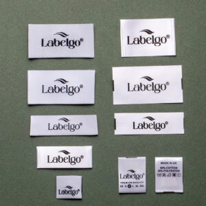 White woven fabric labels with LabelGo logo on grey surface.