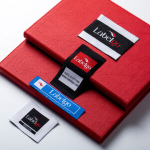 Assorted woven clothing labels arranged on red material.