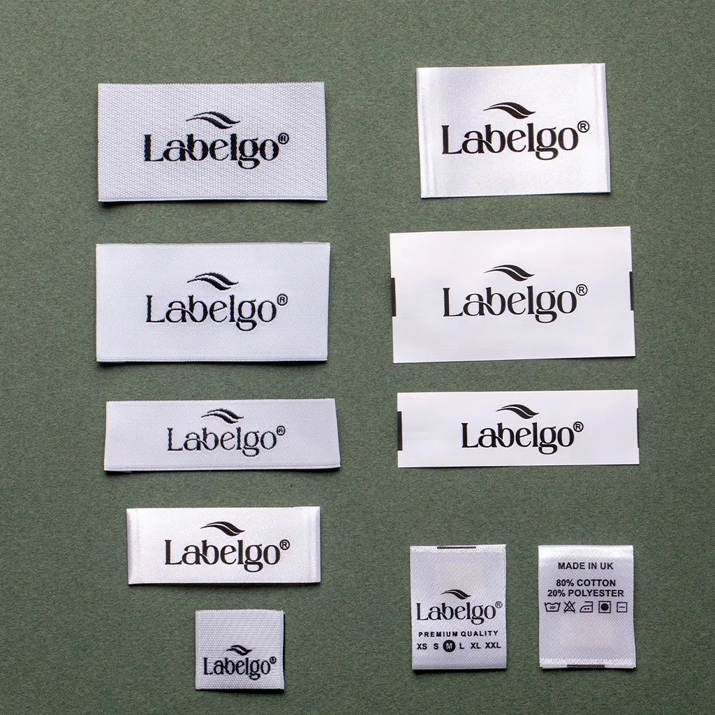 Custom Clothing Labels 31 White woven fabric labels with LabelGo logo on grey surface.